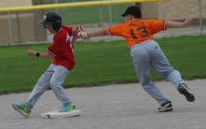 By his chinny chin chin, Angels baserunner Isaac (2) [left] beats the outstretched tag attempt of Orioles second baseman Ethan (13) to complete a deft theft of second base during a 2026 TPBA House League Baseball 11U Mosquito Division Tournament Round Robin Game at Christie Pits Diamond 3.